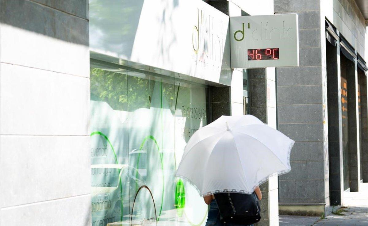 Una mujer pasea protegida por un paraguas en Lleida.