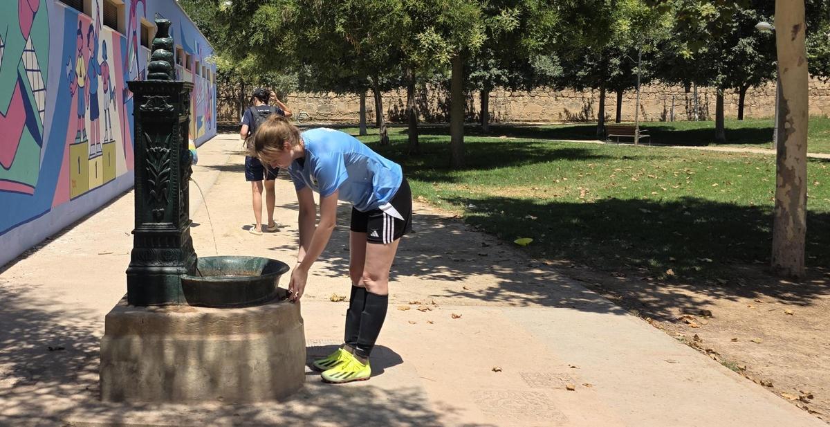 Una futbolista busca el alivio de una de las fuentes públicas