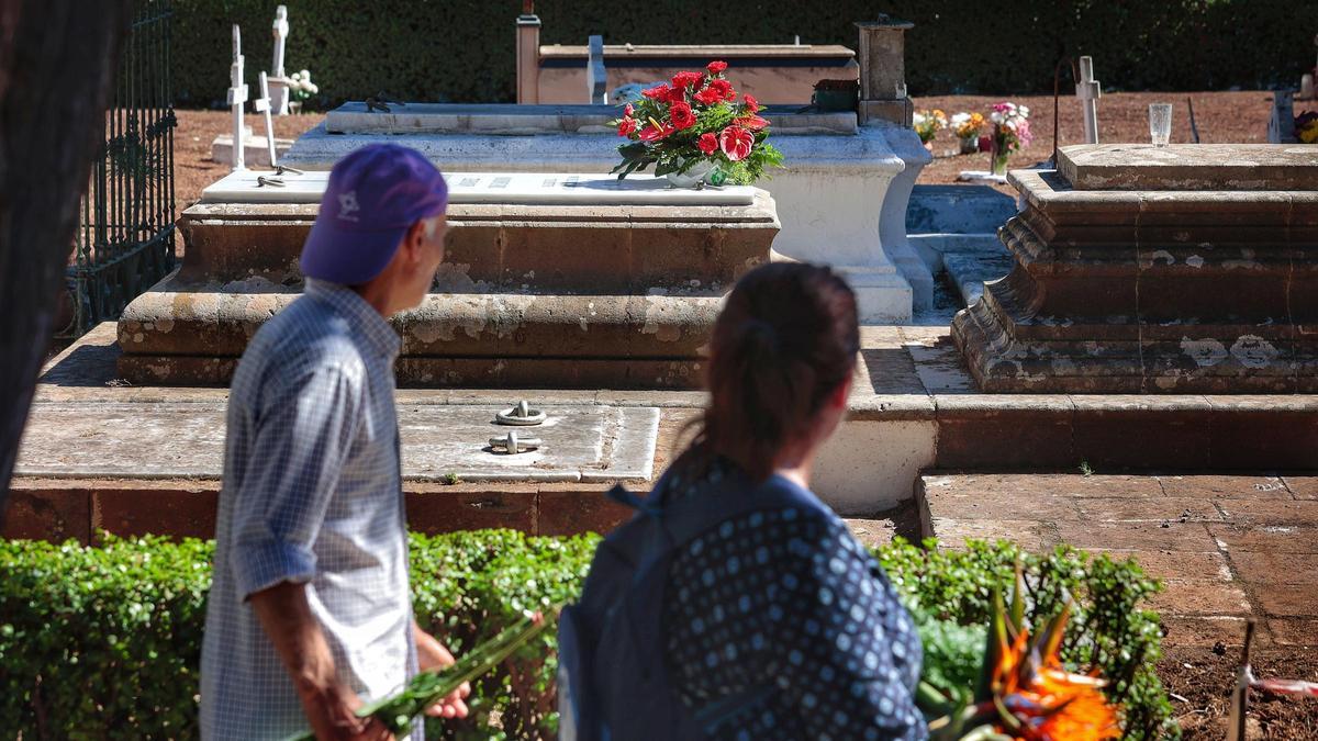 Dos personas van a enramar a sus difuntos en el cementerio de San Juan, en el municipio tinerfeño de La Laguna.