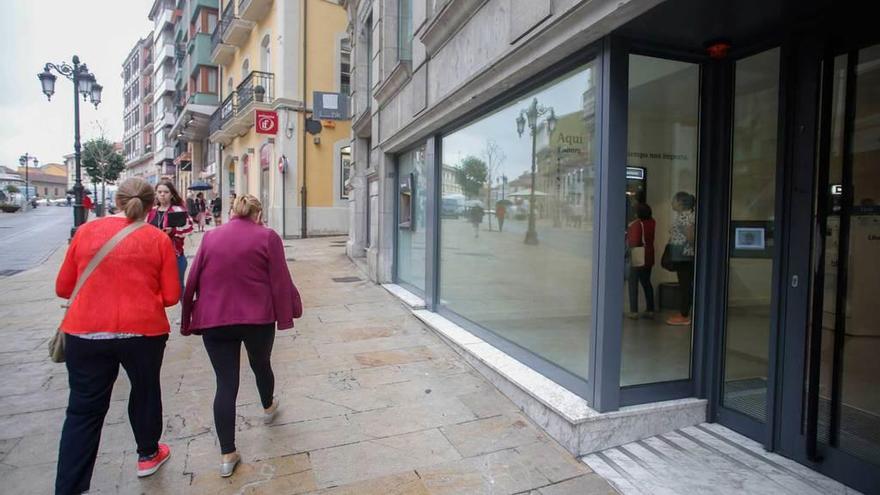 Arriba, clientes entrando en la oficina central de Liberbank en Oviedo. Sobre estas líneas, agencia de la calle la Cámara de Avilés.