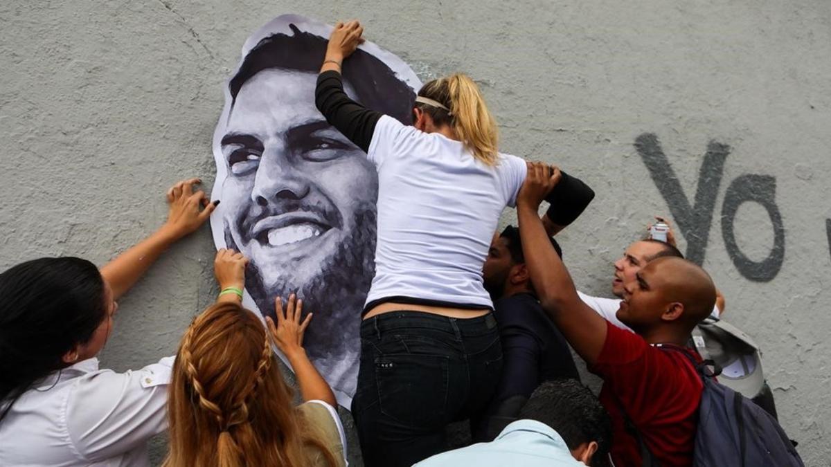 Unos manifestantes colocan un retrato del diputado Juan Requesens, en una pared de Caracas.