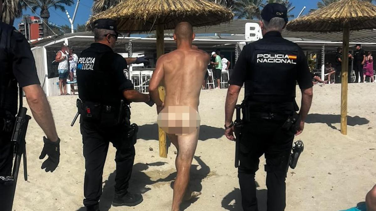 Dos policías, con uno de los turistas denunciados por ir desnudos.
