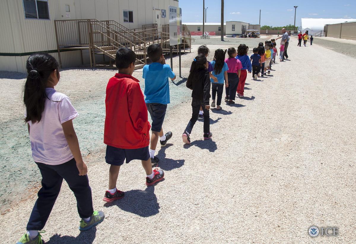 Unos niños caminan en fila hacia sus clases en el Centro de Detención Familiar de migrantes en Dilley, Texas.