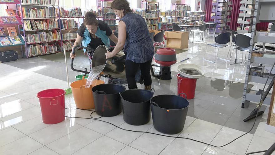 El personal trata de evacuar el agua acumulada en la sala de la biblioteca Luis Seoane, ayer. // Faro