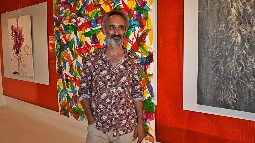 Manuel Rodríguez Méndez ante una de sus coloridas obras de colibríes.