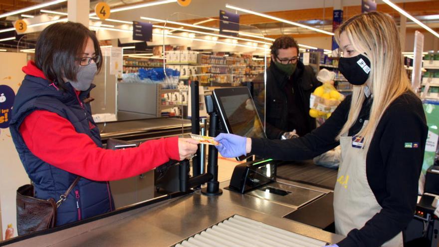 Una caixera entrega un número de la Grossa a una clienta del supermercat