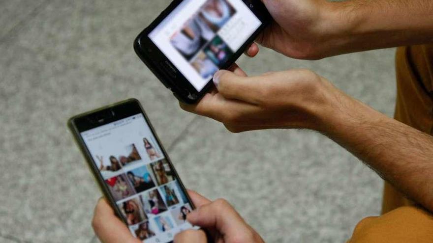 Dos jóvenes visionan fotos de contenido sexual en sus móviles.