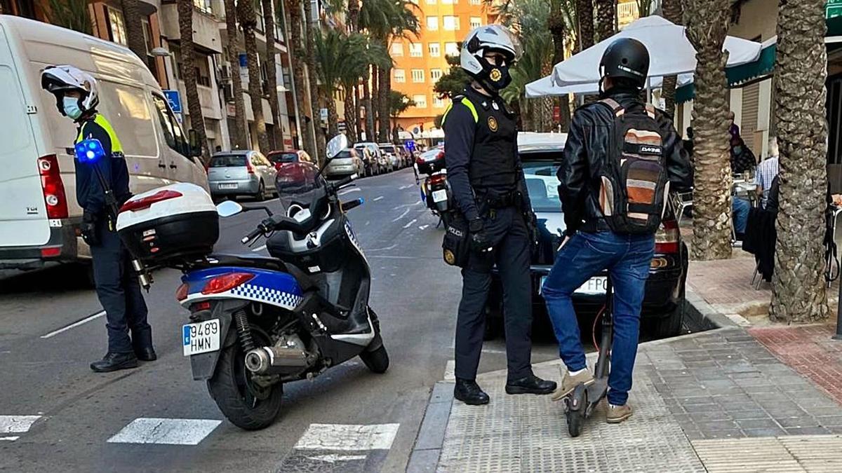 Unos agentes municipales explican a un usuario por qué vías puede circular en Alicante.  | C. P.