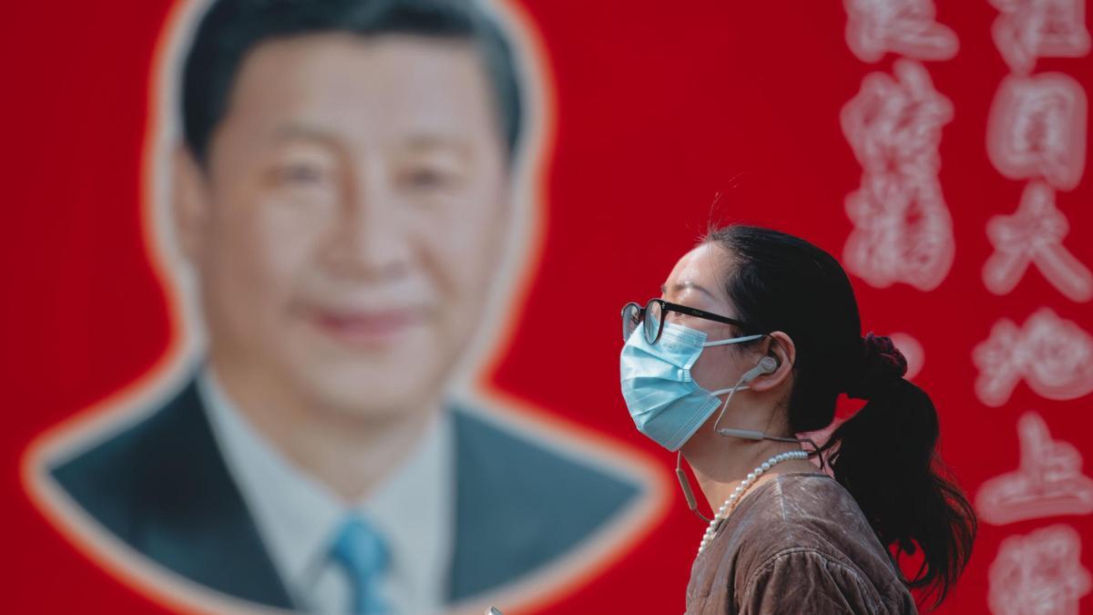 Una mujer pasa ante un mural con el rostro del presidente chino, Xi Jinping, en Shanghai.