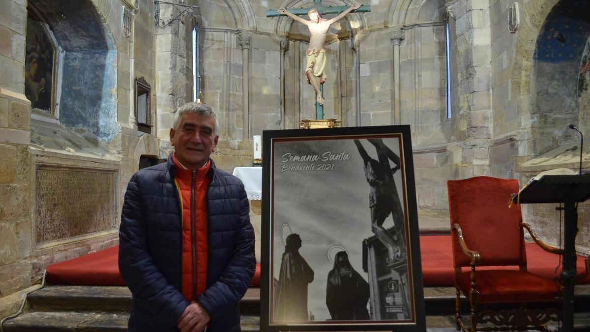 El benaventano Modesto Viejo posa en la iglesia de San Juan junto a su imagen, que ilustra este año el cartel de Semana Santa. / E. P.