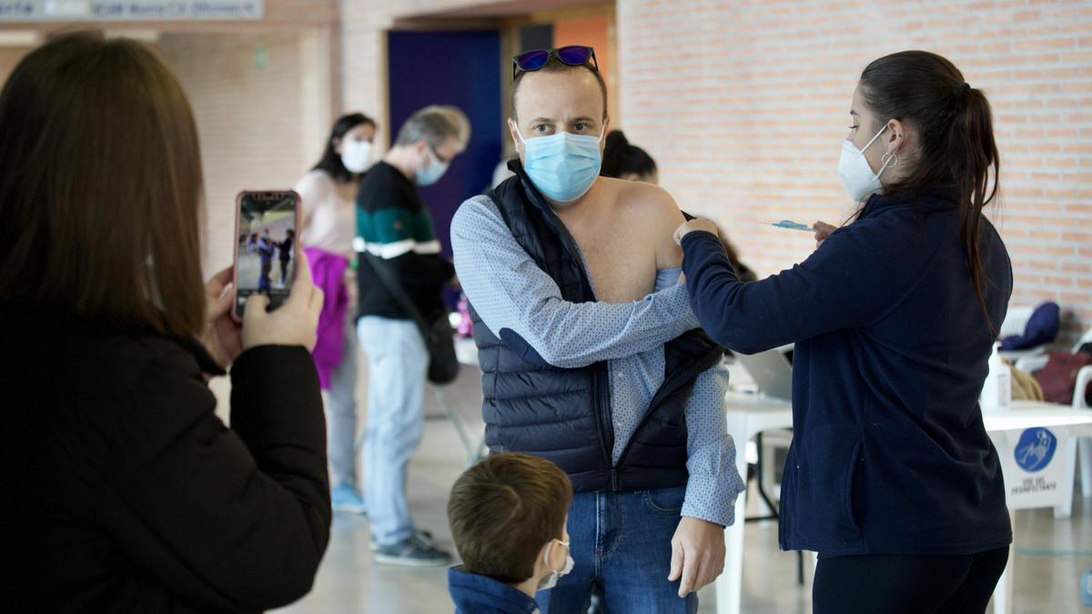 Una persona fotografía a otra mientras recibe el pinchazo, este sábado en Murcia.