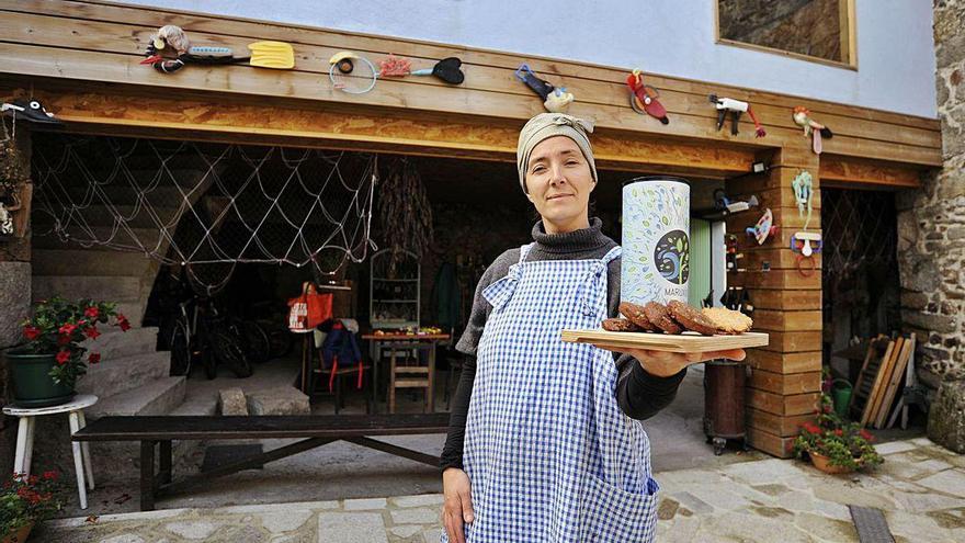 María Rivas posa delante de su casa con algunos de los productos que comercializan.
