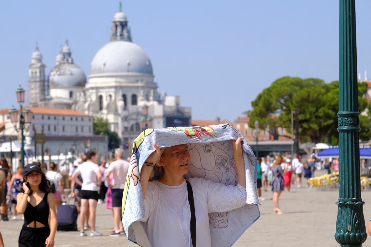 Una persona se protege del calor bajo una toalla, durante la intensa ola de calor, en Venecia