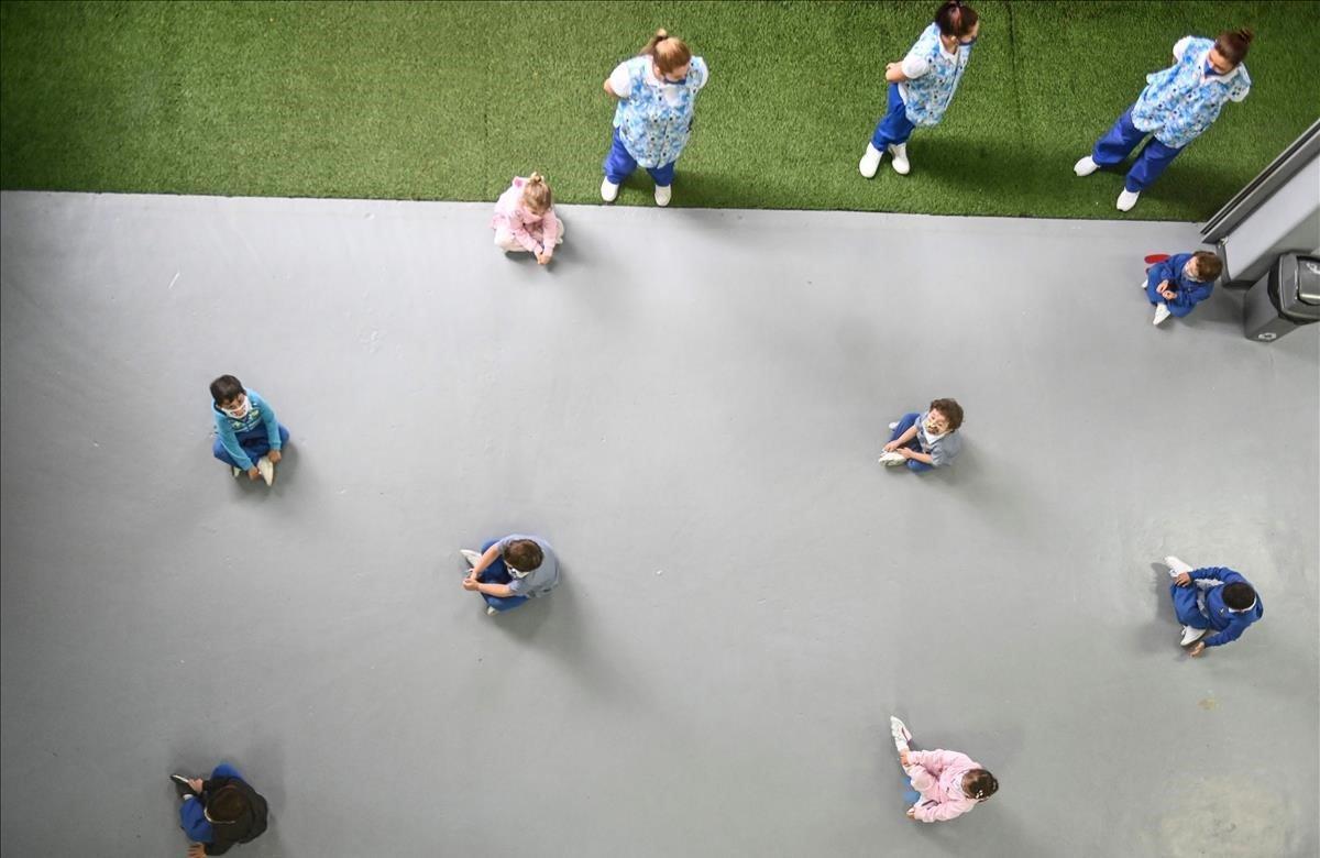 Los niños se sientan en el suelo practicando distancia física en el Kindergarten de Chiquilandia, Medellín. Colombia.