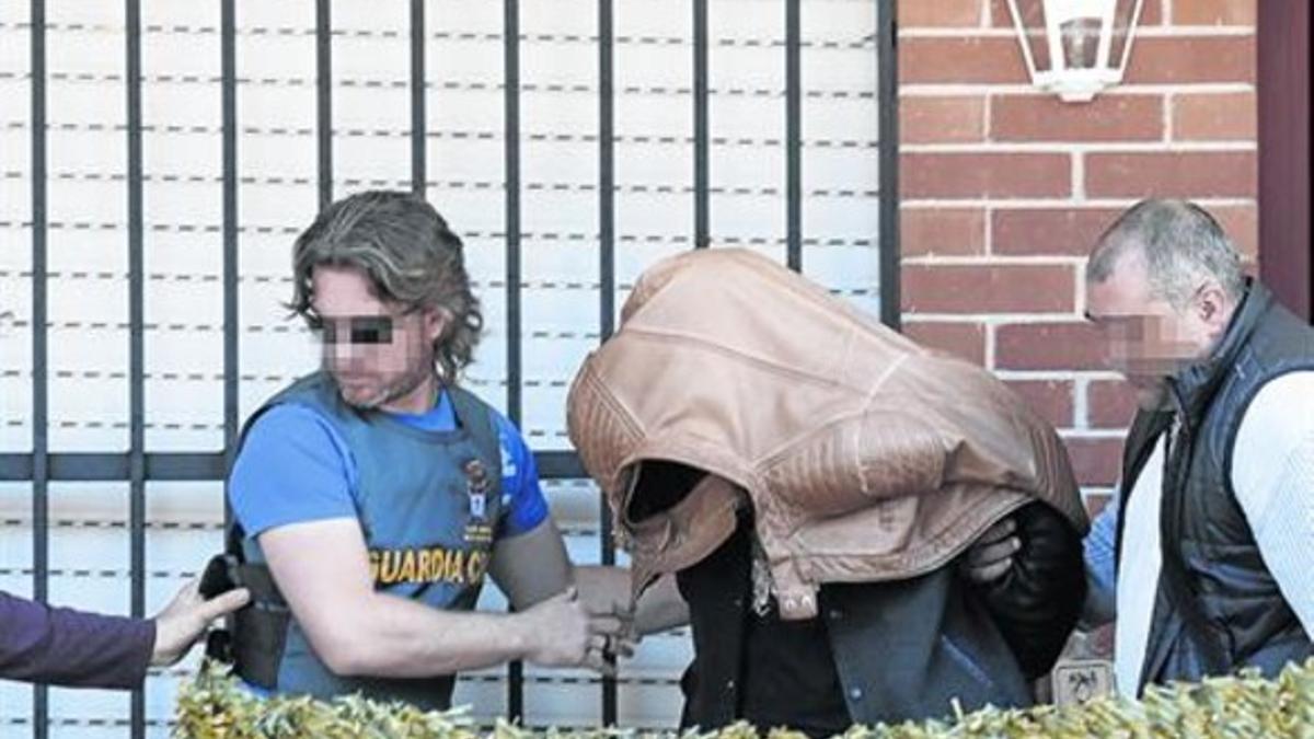 Un momento del registro en la casa pareada de Majadahonda, con el sospechoso escoltado por los agentes.