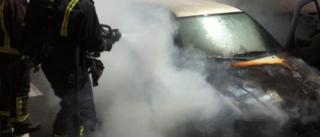 Bomberos apagan el fuego en un coche en la calle Pedro Doblado Claveríe.