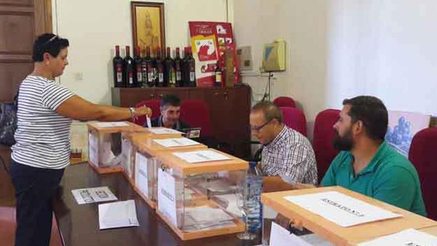 Una mujer ejerce su derecho a voto ante la atenta mirada de los miembros de la mesa electoral.