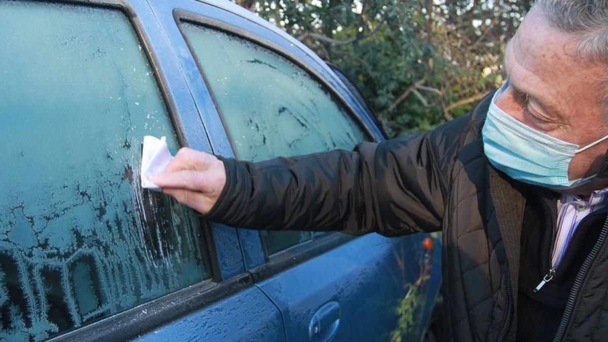 Un vecino retirando el hielo de su coche en la ciudad.   | // IÑLAKI OSORIO