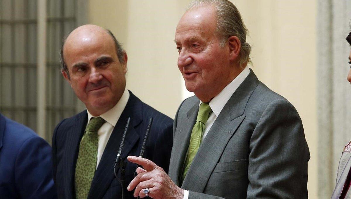 El entonces ministro de Economía, Luis de Guindos, y el rey Juan Carlos, en junio de 2014, en la entrega de un premio.