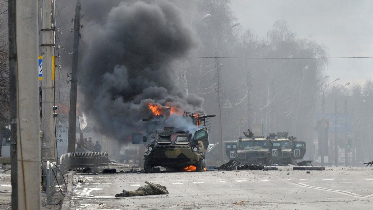 Un vehículo blindado de transporte de personal ruso ardiendo junto al cuerpo de un soldado no identificado durante una lucha con las fuerzas armadas ucranianas en Kharkiv.
