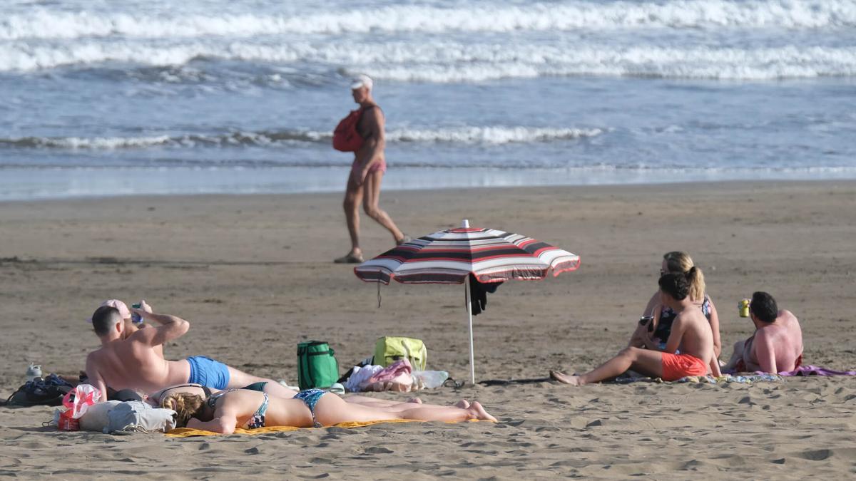 Un grupo de personas toma el sol en Playa del Inglés, Gran Canaria.