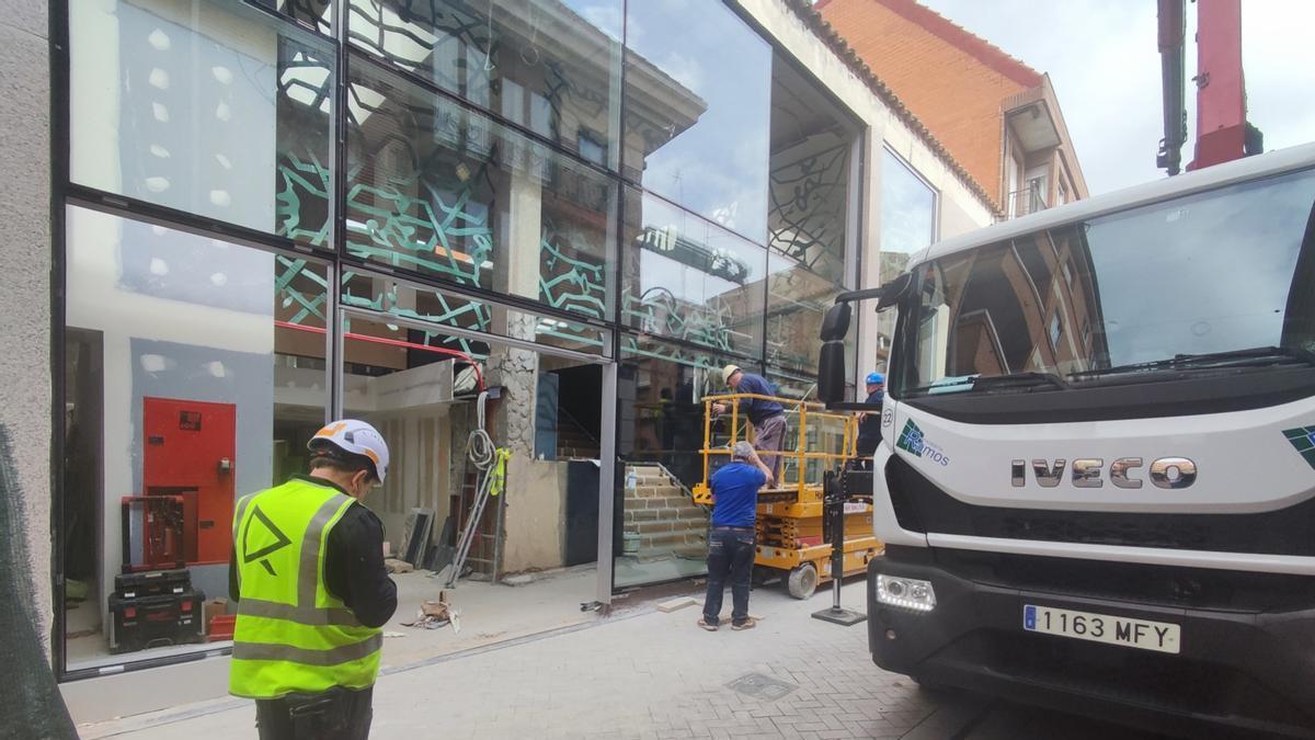Operarios intalando uno de los enormes módulos de cristal de la estructura de acceso al futuro edificio de usos múltiples.