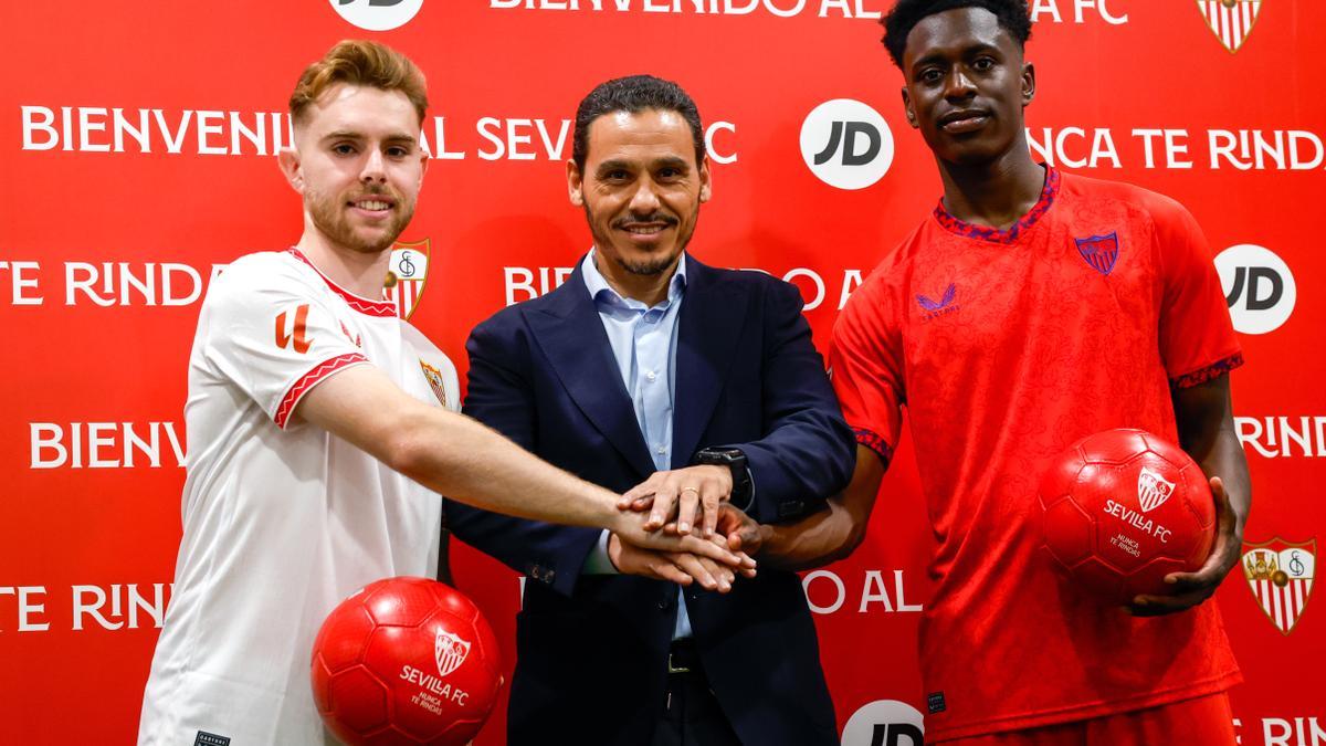 El presidente del Sevilla FC, José María del Nido Carrasco (c), posa junto a los futbolistas Gerard Fernández 'Peque' (i) y Sambi Lokonga (d), vestidos con las equipaciones del club durante su presentación este lunes en el Estadio Sánchez Pizjuan como nuevos jugadores sevillistas.