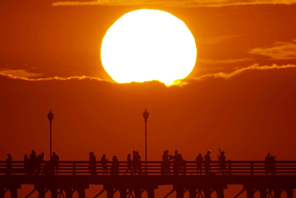 La gente pasea frente a una puesta de sol en un muelle de Oceanside, California.