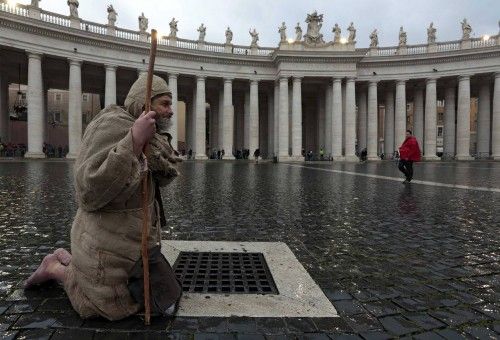 Un hombre vestido de monje se arrodilla en la plaza de San Pedro al comienzo del cónclave para elegir al sucesor de Benedicto XVI