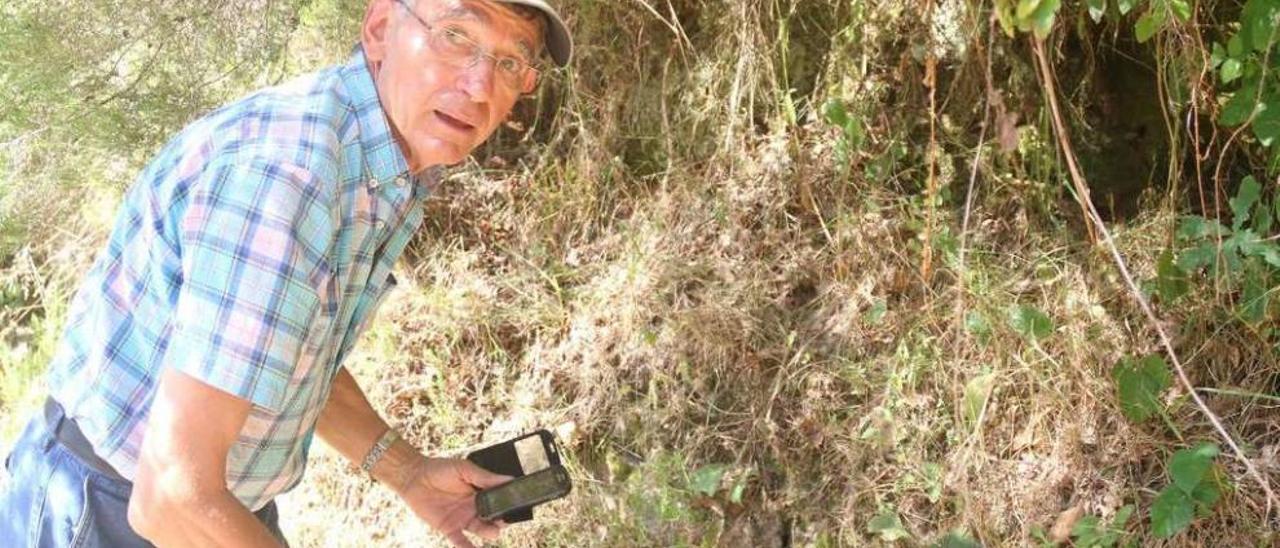 Manuel González Taboada mustra el hueco por el que descubrió el cementerio. //Bernabé