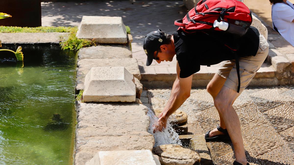 Un turista se refresca en una fuente de Córdoba.