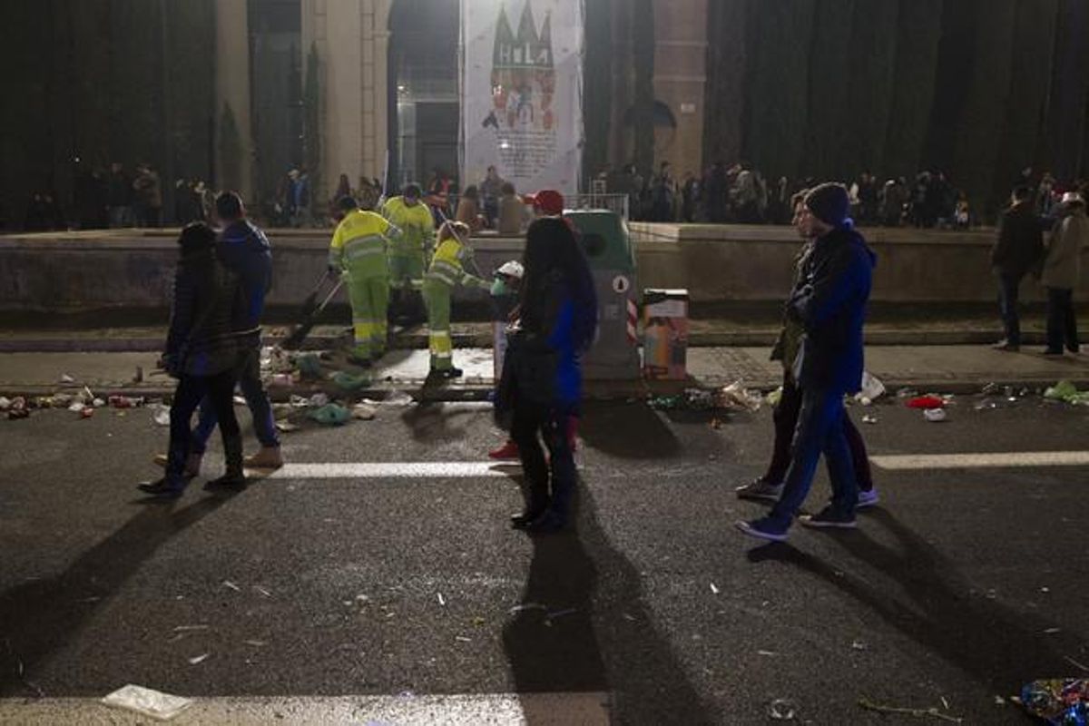 Els serveis de neteja treballen entre ciutadans que abandonaven l’avinguda de Maria Cristina de Barcelona després de la festa d’inici del nou any.