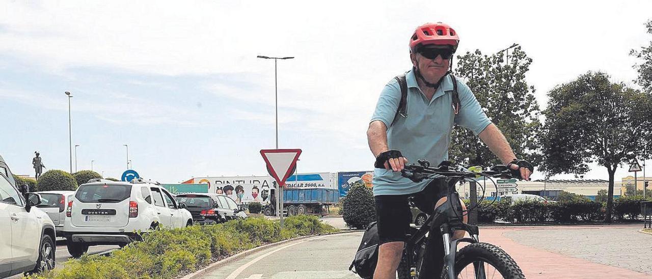 Un ciclista avanza por un carril bici en la capital de la Plana, mientras los coches esperan en la rotonda.