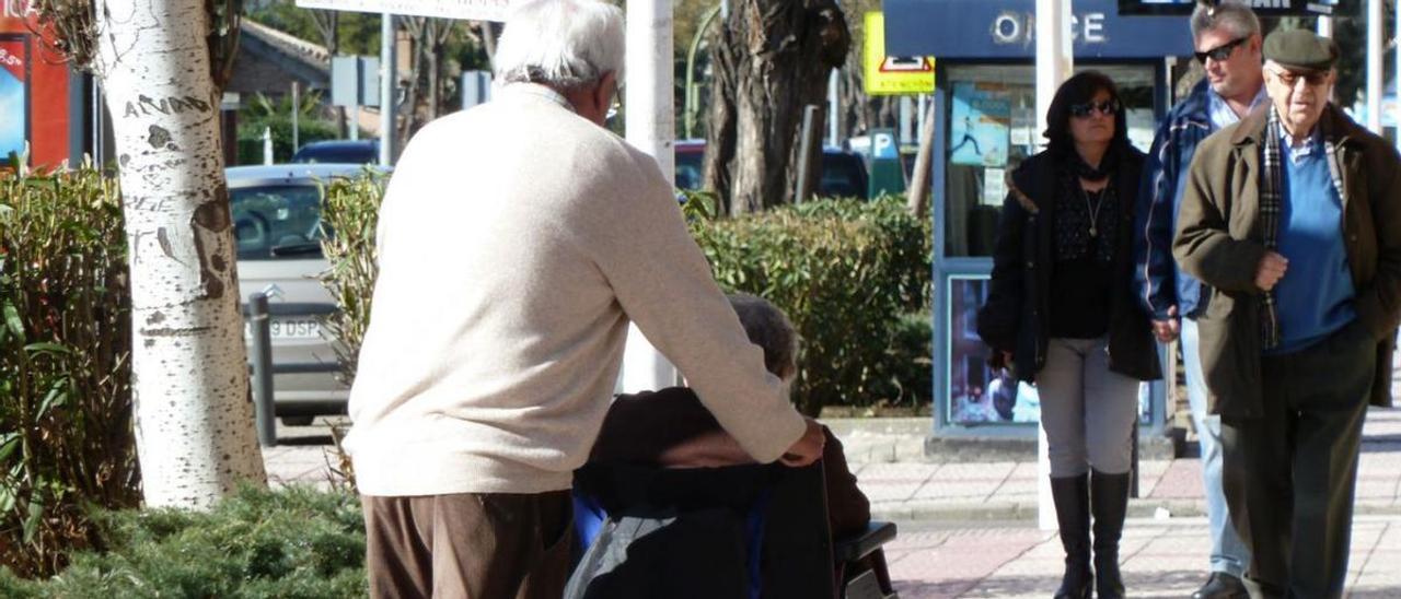 Un hombre pasea a una mujer dependiente en silla de ruedas.