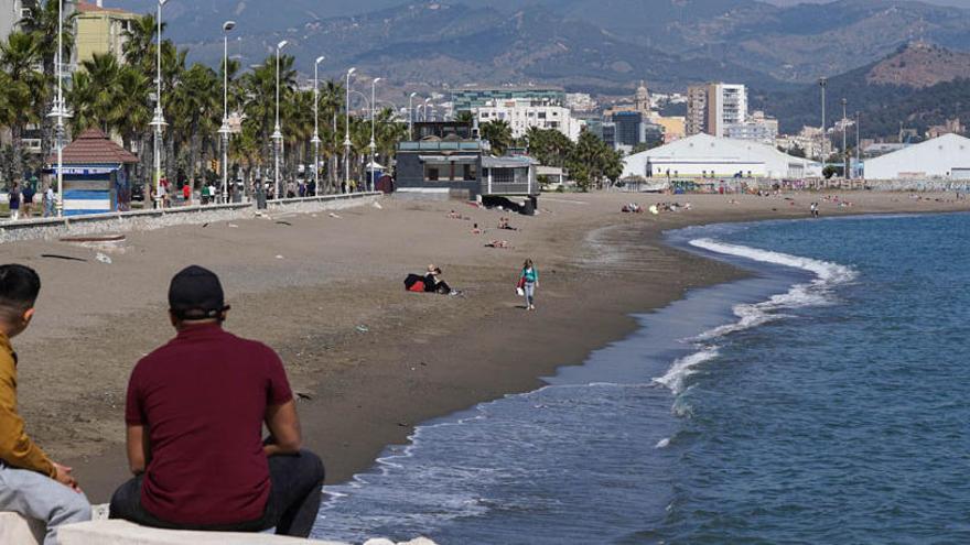 Dos jóvenes observan una prácticamente desierta playa de San Andrés.