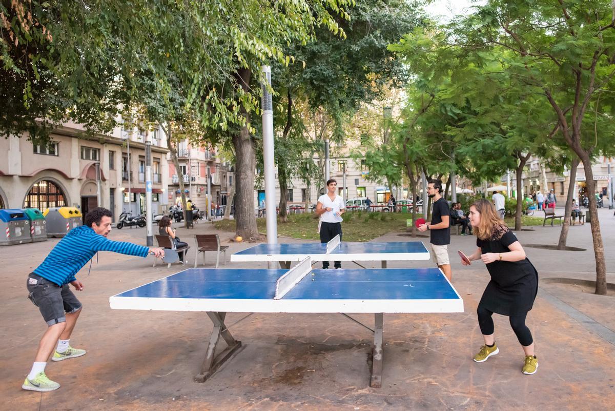 Gente jugando al ping pong en una plaza en la Barceloneta