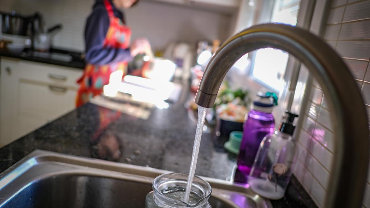 Una vecina cocina mientras llena una jarra con agua del grifo.