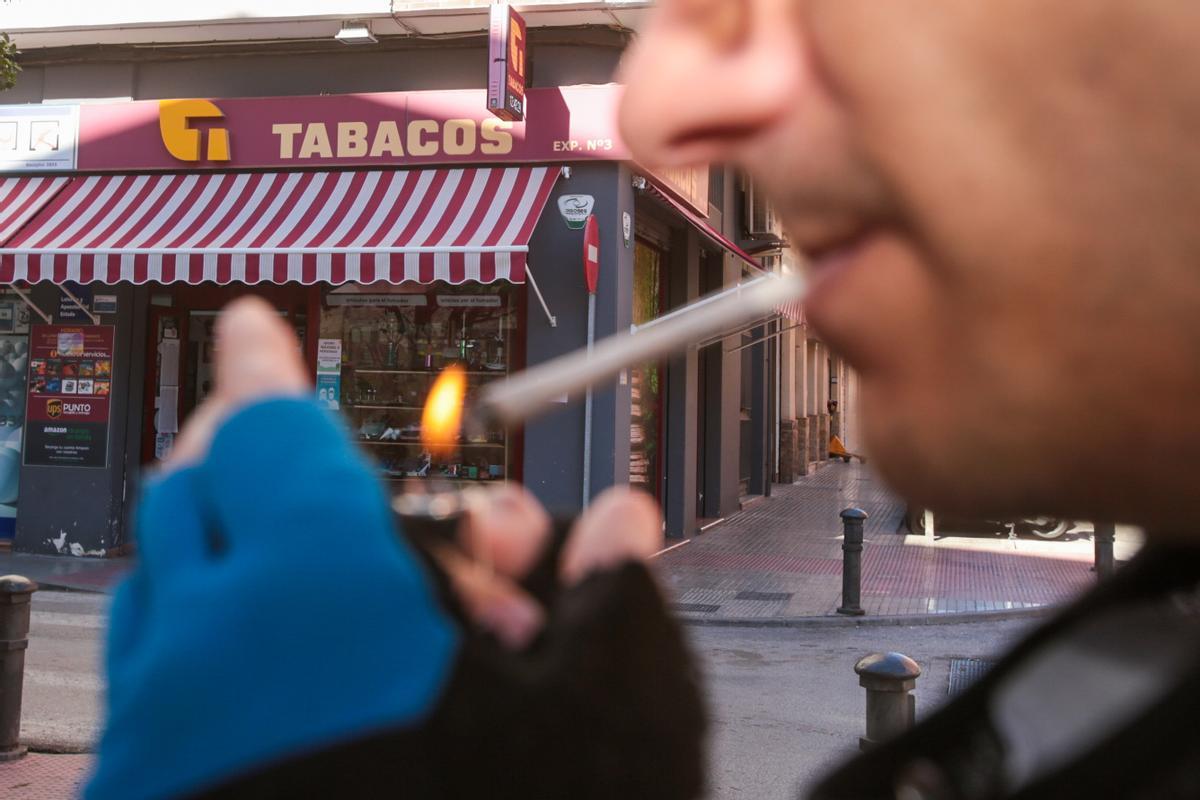 Un hombre fuma frente a un estanco.