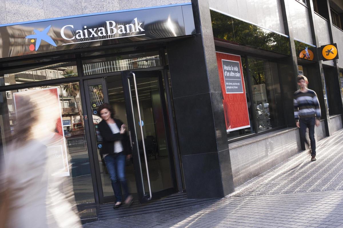 Una clienta sale del interior de una sucursal bancaria.