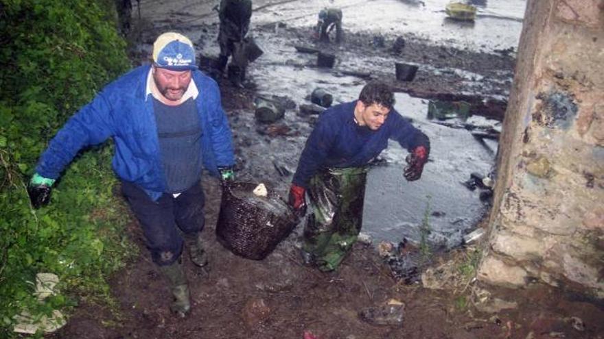 Dos vecinos de Candás sacan galipote de la ensenada de Perán la mañana del 6 de diciembre de 2002.