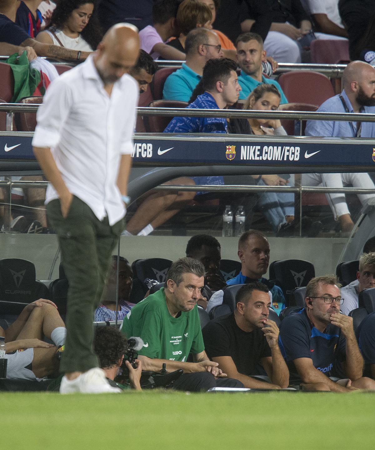 Unzué junto a Xavi en el banquillo mientras Guardiola camina pensativo por la banda. 