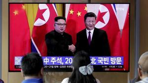 Unos transeúntes observan un programa de TV en el que aparecen el presidente chino Xi Jinping saludando al líder norcoreano Kim Jong-un en Pionyang. 