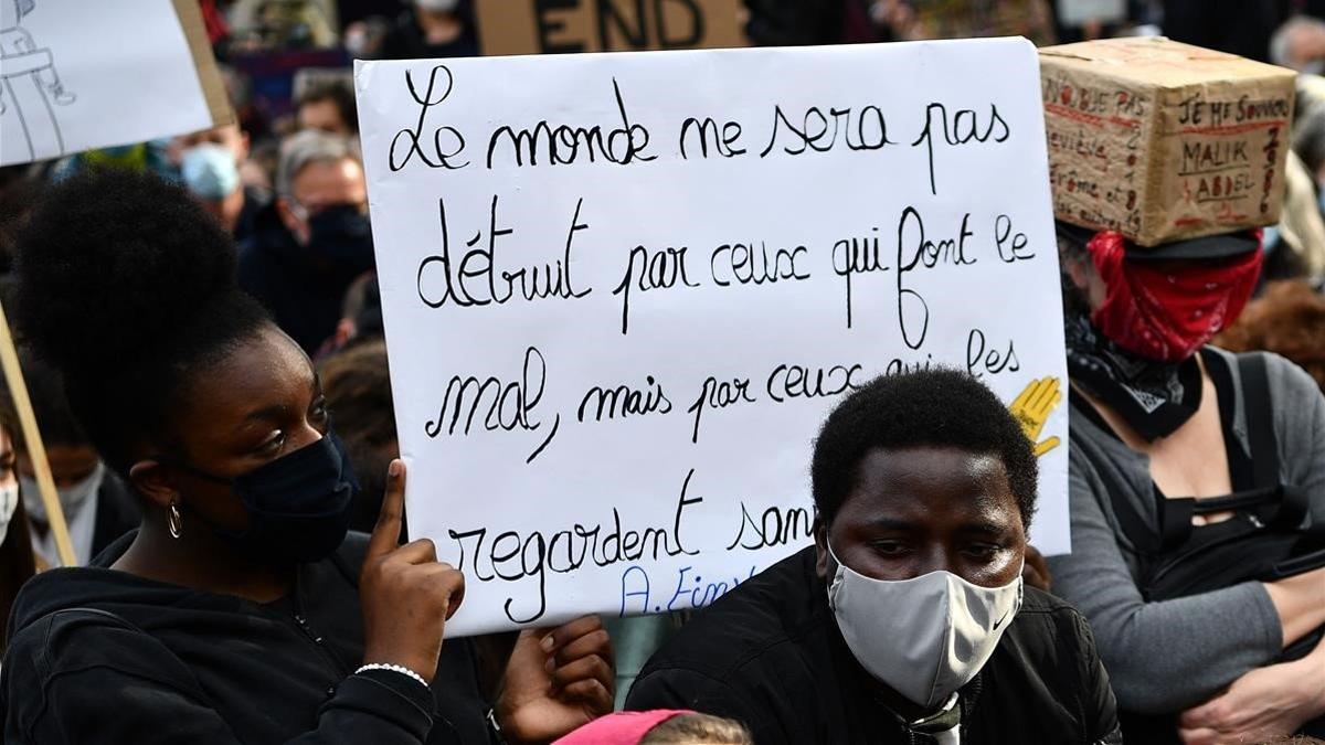 Una mujer sostiene una pancarta en la que se lee: &quot;El mundo no será destruido por aquellos que hacen el mal, sino por los que les miran sin hacer nada&quot;.