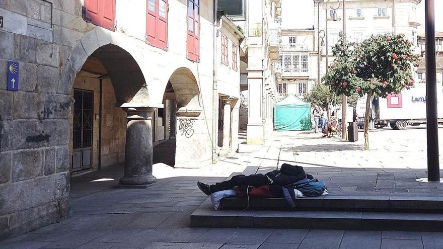 Un hombre duerme en plena Praza da Ferrería, junto a uno de los soportales más afectados.