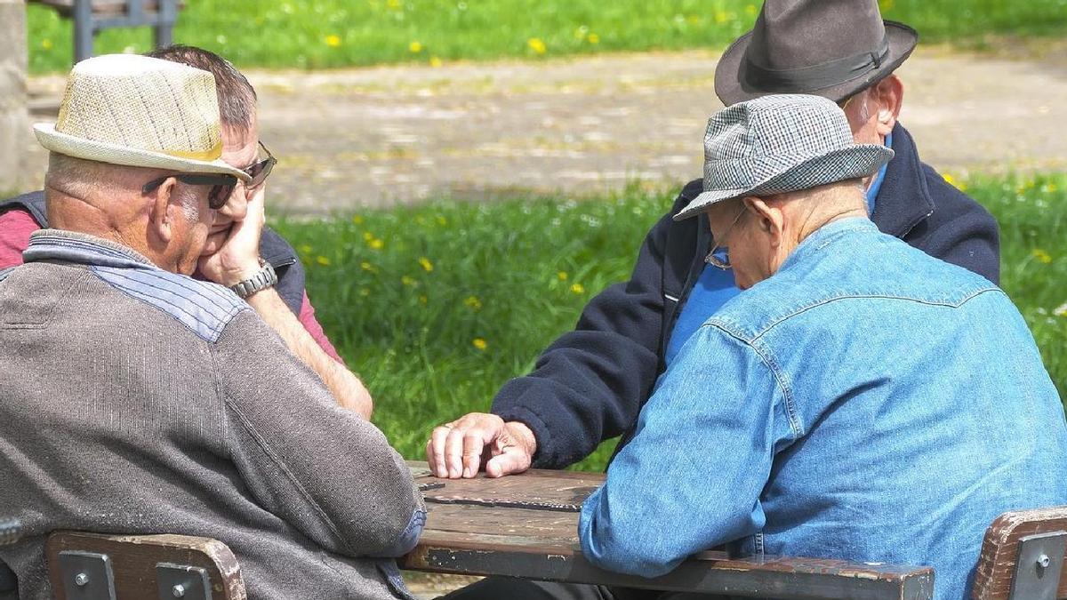 Un grupo de pensionistas disfruta de una partida de dominó en un soleado día.