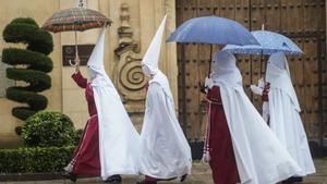 Nazarenos de la Hermandad de La Sentencia se protegen de la lluvia con paraguas en Córdoba (1)