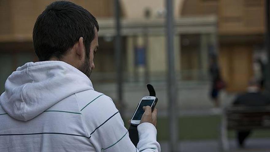 Un joven observa su móvil.