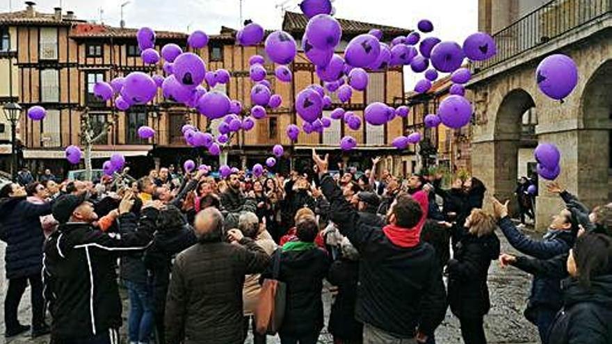 Participantes en la concentración lanzan globos morados en recuerdo de las víctimas.