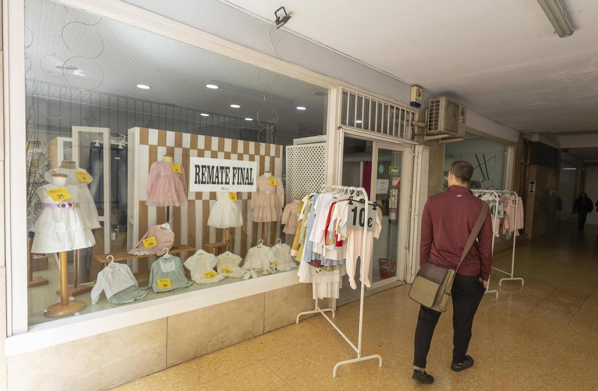 Un hombre pasa por delante de uno de los escaparates de "Neus Modes", que ha entrado en proceso de liquidación antes del cierre.