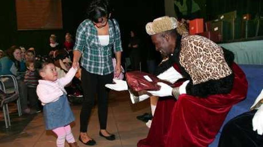 Una niña recibe asustada el regalo del rey Baltasar.